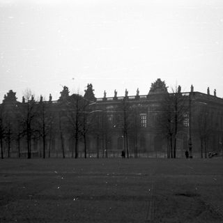 Historic building with bare trees in open area.