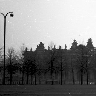 Historic building with bare trees in open area.