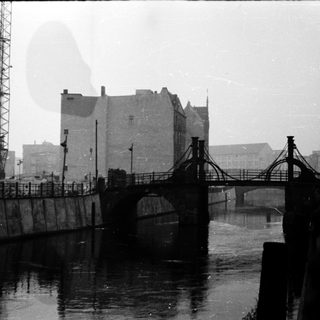 Industrial port scene with bridge, cranes, and foggy waterfront.