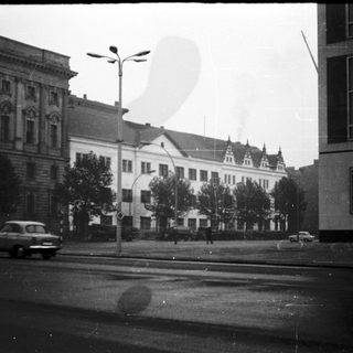 Historic urban street with vintage cars and classic architecture.