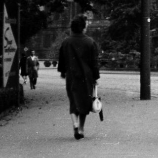 War-damaged city buildings with pedestrians walking.
