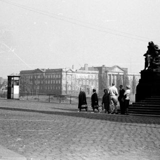 People walking near historic building and bridge.