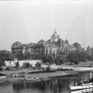 Historic building by river with vintage boat.