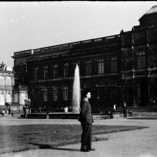 Grand historic building with fountain, man standing.