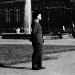 Grand historic building with fountain, man standing.
