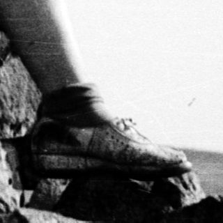 Person sitting on rocks, holding phone.
