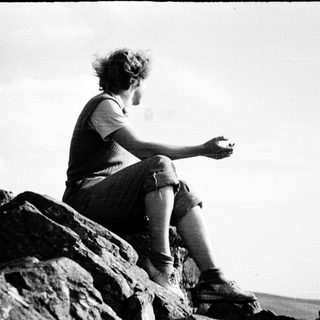 Person sitting on rocks, holding phone.