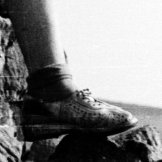 Woman smiling while sitting on rocky cliffside.