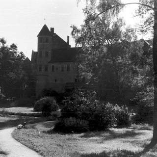 Historic castle in lush, landscaped park setting.