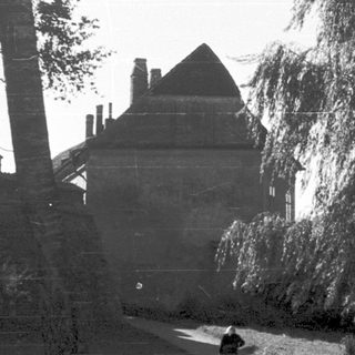 Silhouette of person walking in park near historic building.