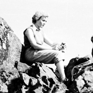 Person sitting on rugged rocky summit.