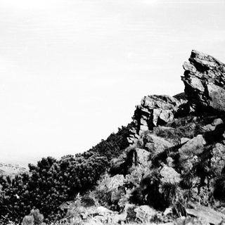 Rugged rocky cliff overlooking distant landscape.