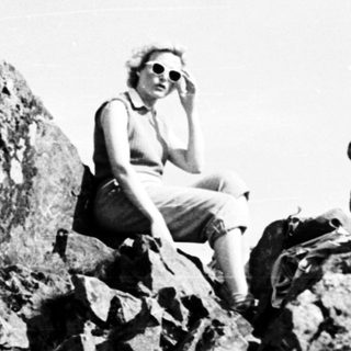 Person sitting on rugged rocks outdoors.