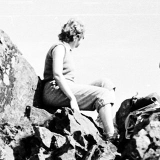 Person climbing or sitting on rugged rocky terrain.