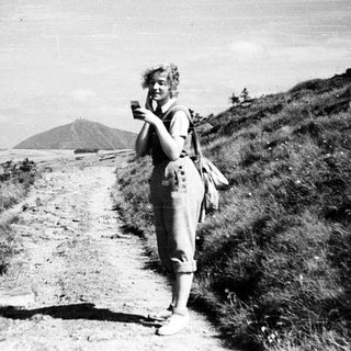 Person hiking on trail with scenic coastal view.