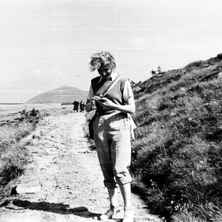 Woman hiking on trail with scenic coastal view.