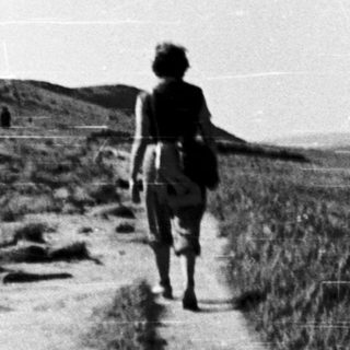 Person hiking alone on a rural dirt path.