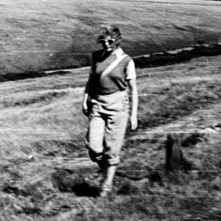 Man in military uniform walking alone in barren terrain.