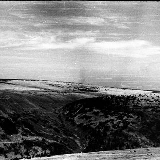 Rural landscape with terraced hills and distant flat terrain.