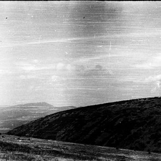 Misty landscape with distant hills and cloudy sky.