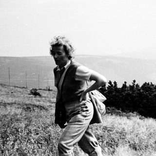 Person hiking uphill through grassy terrain.