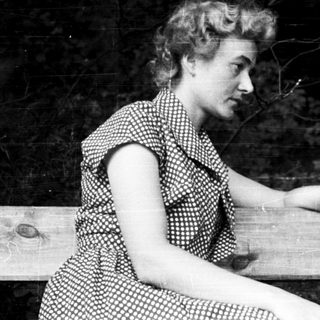 Woman sitting on wooden bench outdoors.
