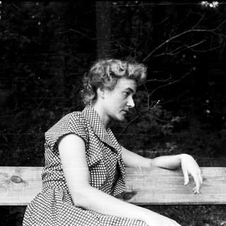 Woman sitting on wooden bench outdoors.