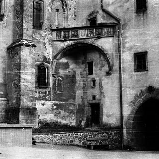 Historic stone building with arched entrance and balcony.