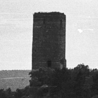 Historic tower ruins on elevated hillside.
