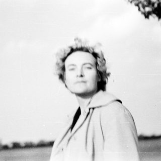 Black-and-white portrait of woman outdoors in vintage coat.