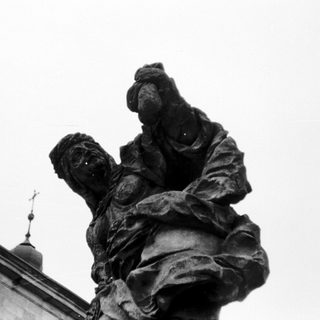 Statue depicting a weary, burdened figure carrying a heavy load.