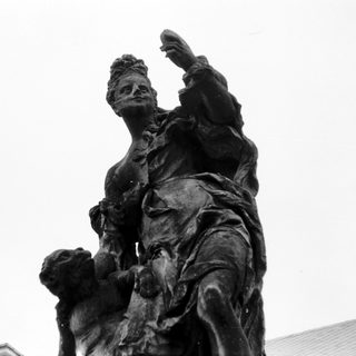 Statue of woman riding horse, raising arm.
