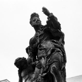 Statue of woman riding horse, raising arm.