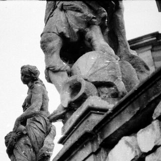 Statue group depicting figures on ornate architectural cornice.