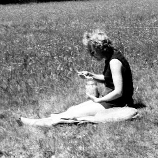Person sitting on grass reading outdoors.