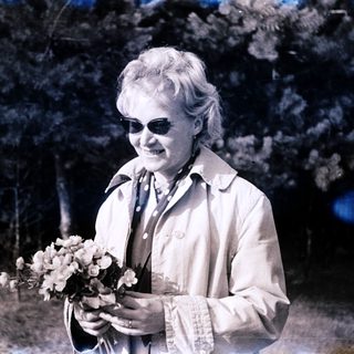Woman holding flowers outdoors in vintage-style photo.