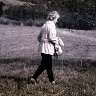 Woman walking alone in rural, open field.