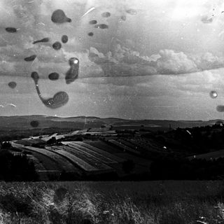 Rural landscape with clouds and smudged glass overlay.