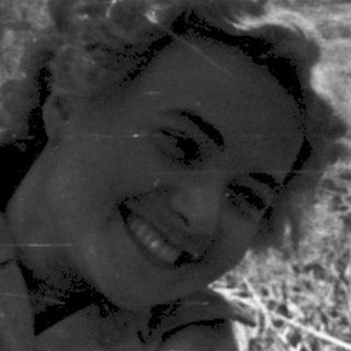 Woman smiling while lying in a field of cut hay.