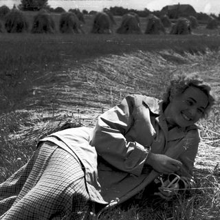 Woman smiling while lying in a field of cut hay.