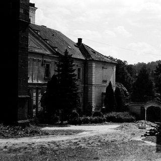 Abandoned estate with old buildings and overgrown grounds.