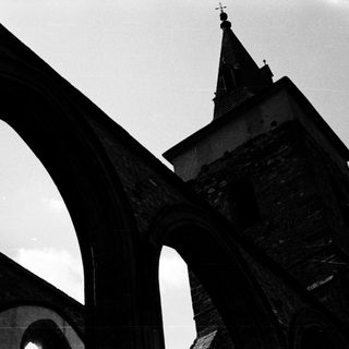 Gothic stone church tower with arched bridge.