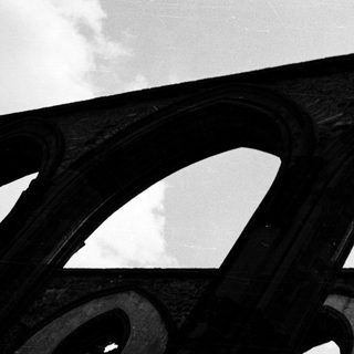 Architectural bridge arches under cloudy sky.