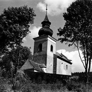 Rural church with onion dome in wooded area.