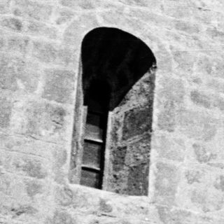 Stone building facade with arched window.