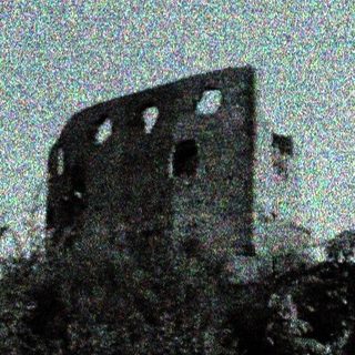 Abandoned stone tower surrounded by trees.