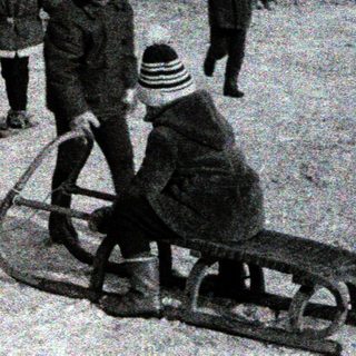 Children sledding in snowy urban area.