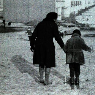 A woman and child walk together in snow.