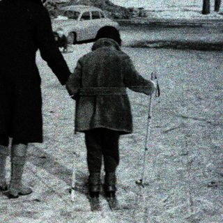 A woman and child walk together in snow.
