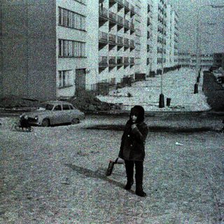 Child standing alone in snowy urban street.